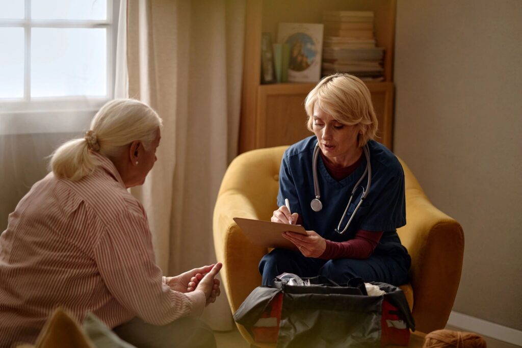 Middle Aged Nurse Taking Notes during Senior Woman Home Visit